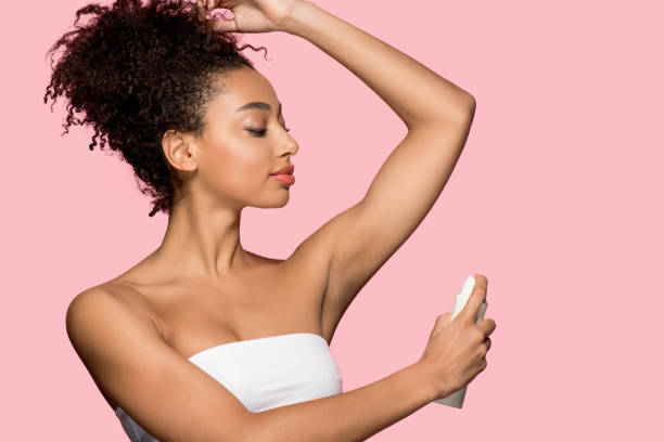 A woman using a body spray in her armpit
