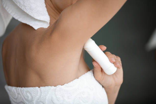 A person applying deodorant to their armpit.